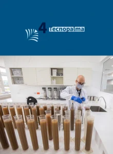 Diapositiva '4 Tecnopalma'. Foto de un investigador trabajando en un laboratorio con una fila de grandes probetas con muestras.