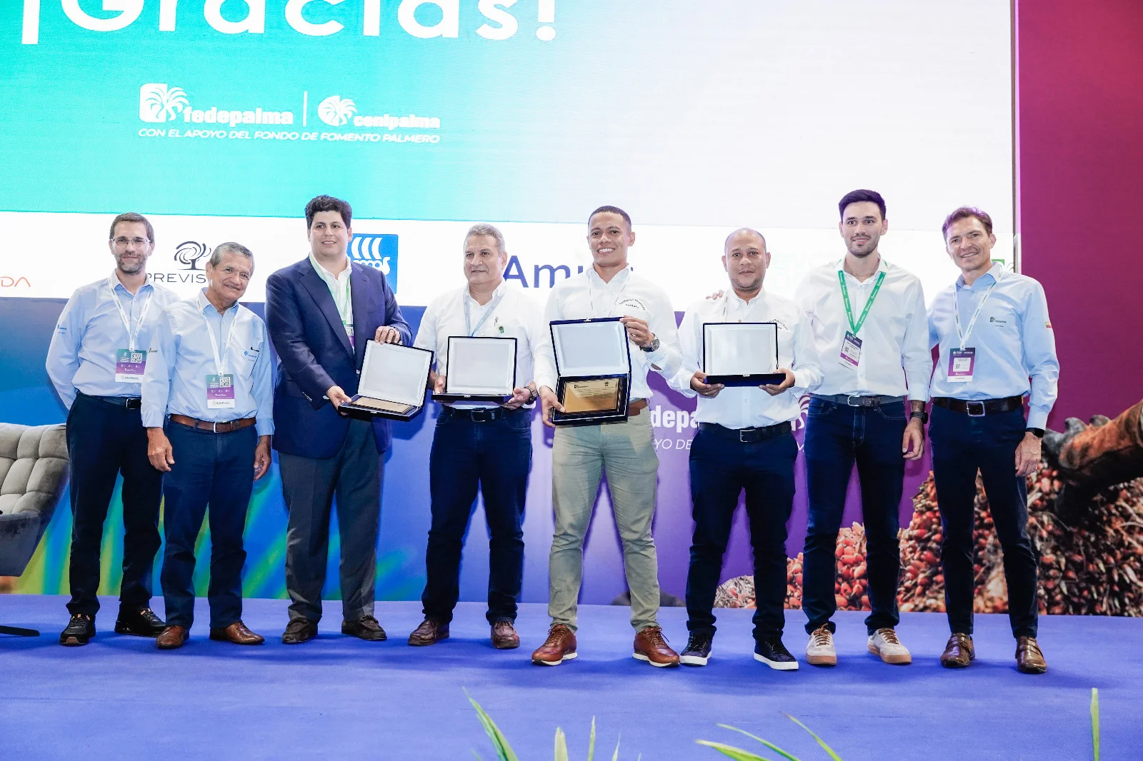 Ocho hombres posando en un escenario mientras sostienen premio de sostenibilidad